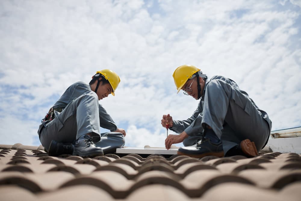 Two People doing Roof Repair on a tile roof